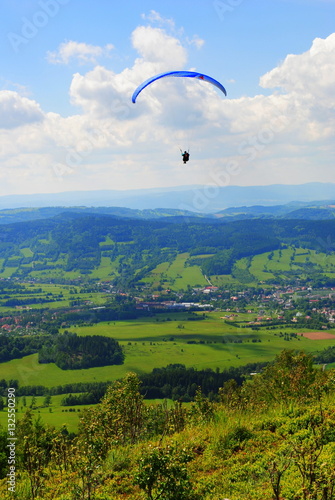 Paralotniarz nad górami na tle błękitnego nieba