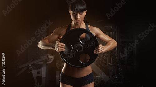 Fitness muscular woman strong hand Pumping up muscles with plate