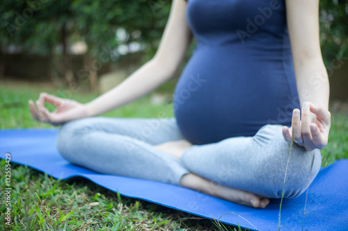 Fototapeta Naklejka Na Ścianę i Meble -  Close up of pregnant woman yoga  in garden
