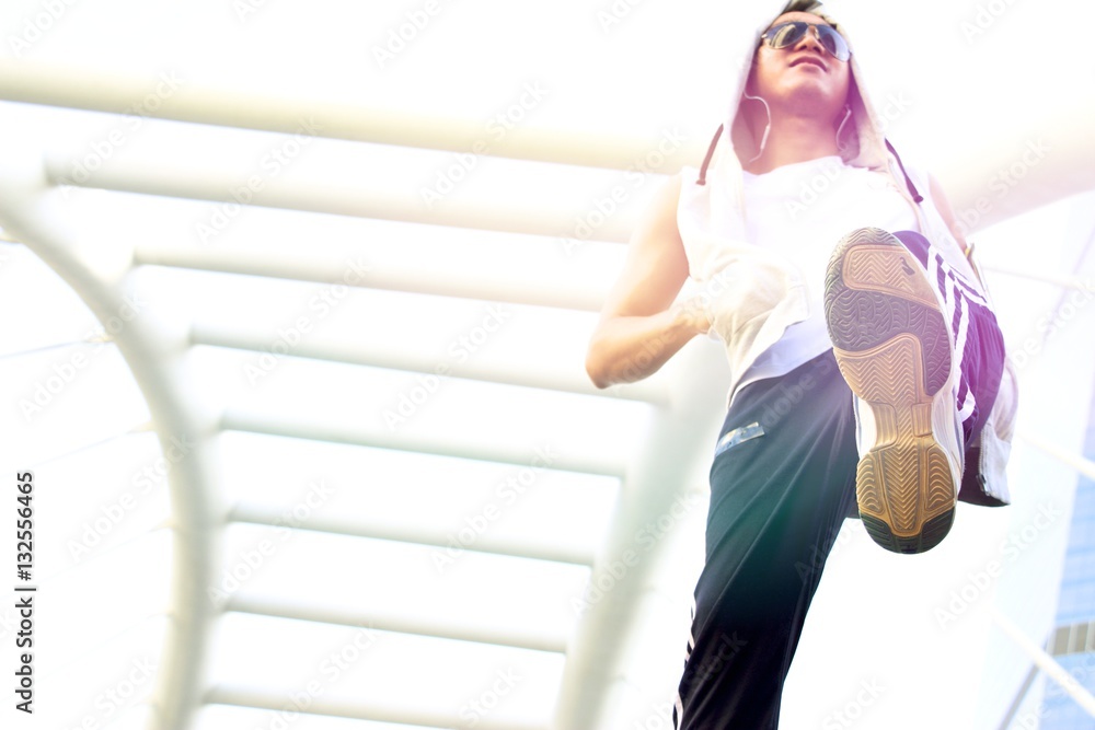 Obraz premium A man in sport wear is warming up his body during exercise jogging in the city.