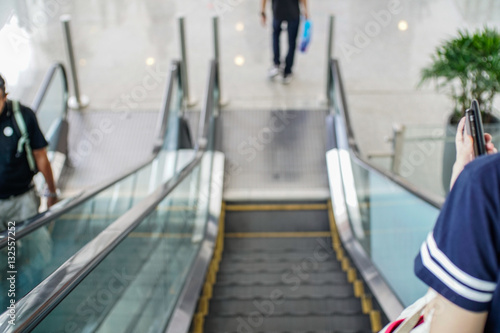 Abstract blurred image of people moving down on escalator