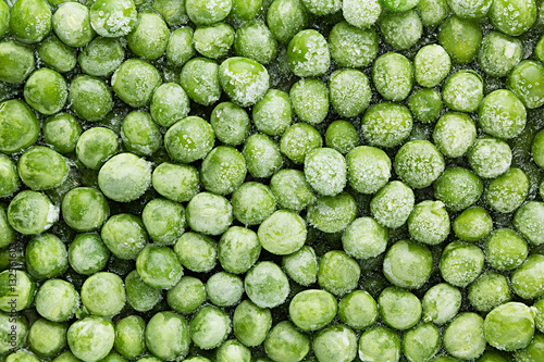 Fresh frozen green peas with hoarfrost closeup as background. Healthy vitamin food.