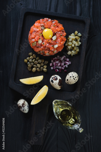 Salmon tartar on a black wooden serving tray, high angle view