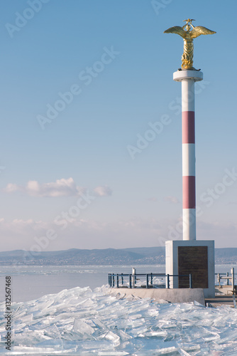 Texture of ice surface, cracked ice floating on blue water, seasonal winter landscape.Ice covered pier at Lake Balaton.