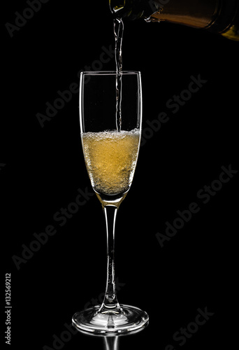 champagne pouring in glass from bottle isolated on black backgro