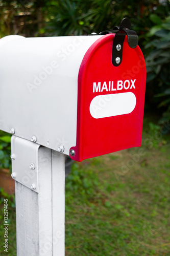 Red and white mail box white green garden background
