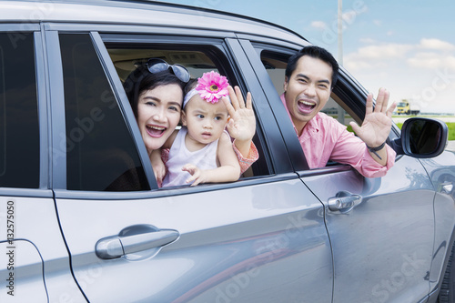 Cheerful family waving hands in the car © Creativa Images