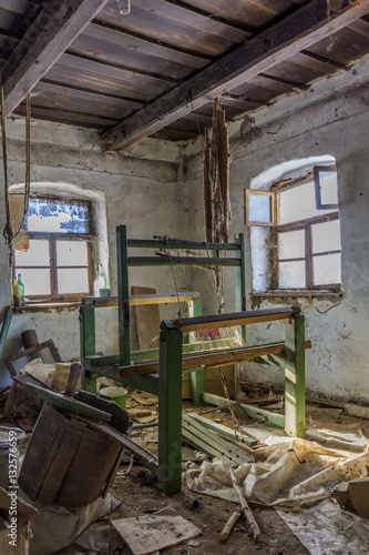 Damaged vintage weaving machine in an old abandoned house with grunge wall and wooden ceiling.