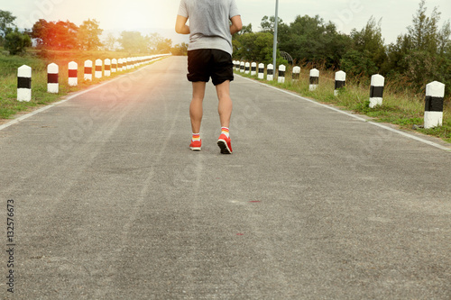 Fototapeta Naklejka Na Ścianę i Meble -  athletic young man running on road in the park. Healthy lifestyl