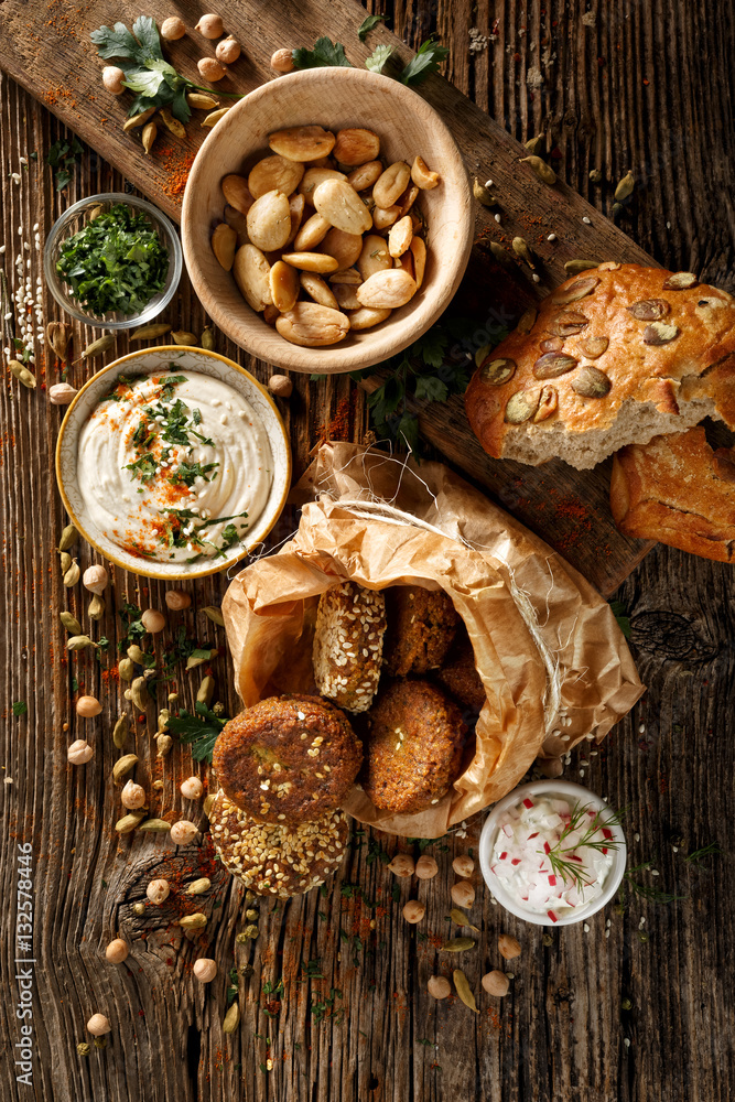Fototapeta premium Falafel, delicious dips and roasted almonds, excellent vegan appetizers on rustic wooden table, top view