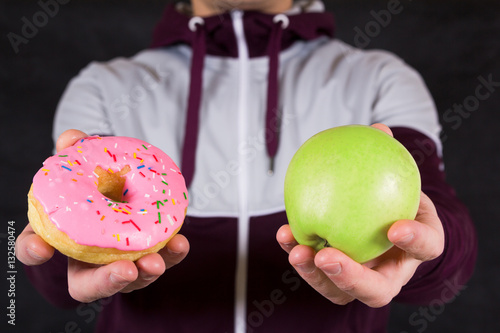 Photography Man offering apple and donut as concept of healty lifestyle