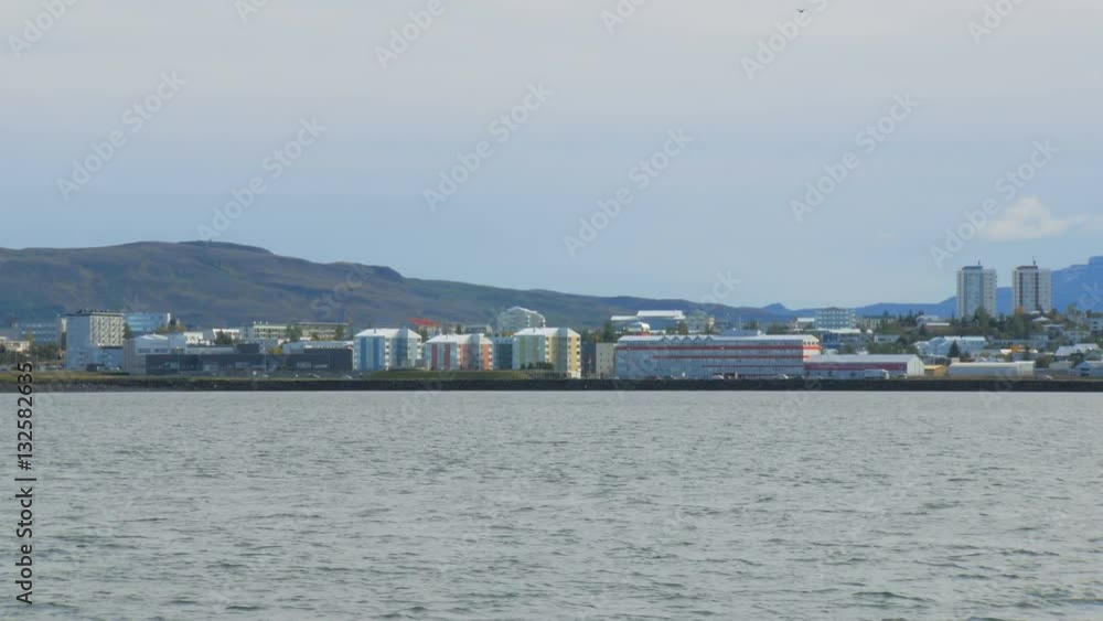view of Reykjavik with modern buildings, moving cars, large mountain is on background, northern city view of Reykjavik with modern buildings, moving cars, large mountain is on background, northern city
