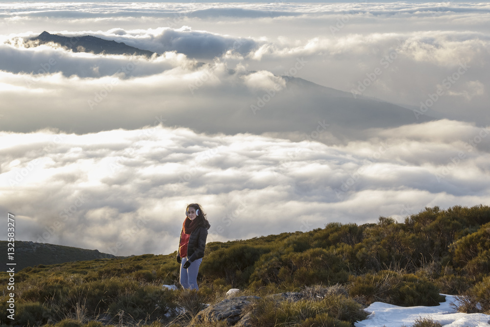 Obraz premium Momentos de libertad. Mujer mirando a cámara en la montaña con el mar de nubes a sus pies
