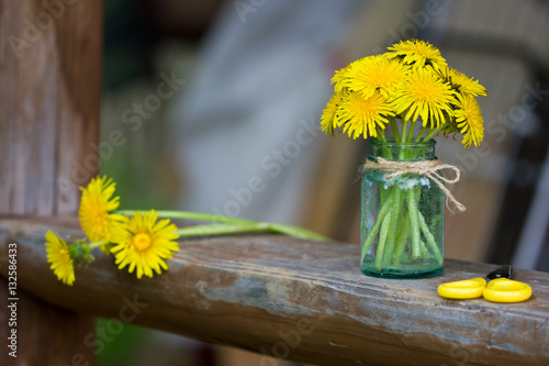 Fototapeta Naklejka Na Ścianę i Meble -  Yellow wildflowers in a glass jar. A bouquet of dandelions.