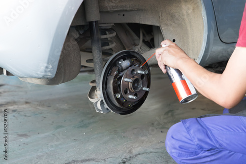 mechanic spray chemical to clean brake