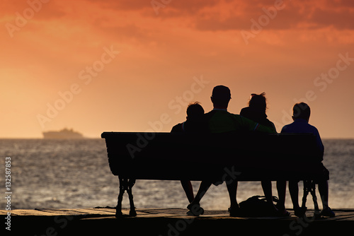 Silhouette of family on a bench by the sea, people relaxing at the seaside during holiday