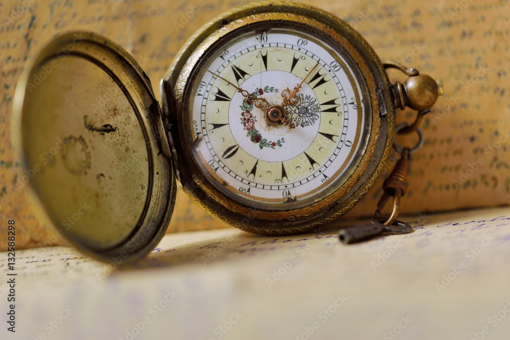 Old pocket watch with key and old letters background