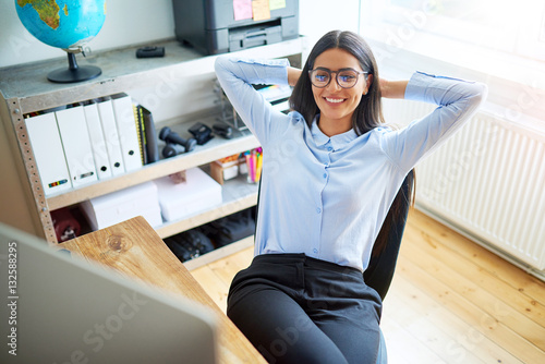 Woman leaning back in chair at work photo