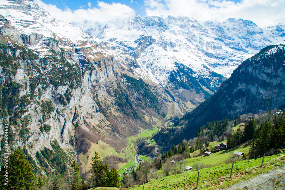 The Snow-covered Swiss Alps in background and Green field at Murren Village, Jungfrau region, Switzerland - April, 2016 The Snow-covered Swiss Alps in background and Green field at Murren Village, Jungfrau region, Switzerland - April, 2016