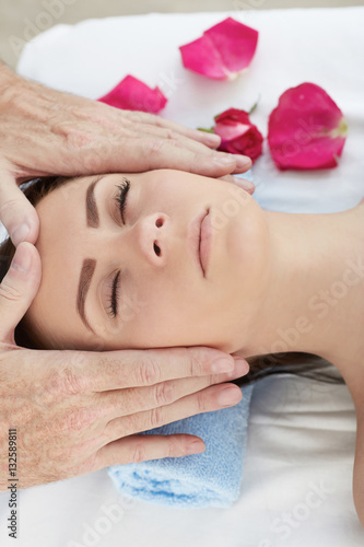 Beautiful young girl having face massage in spa salon.
