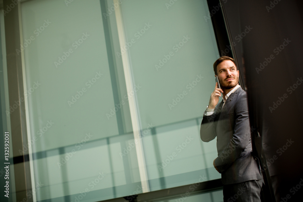 Young man with mobile phone by office building Young man with mobile phone by office building