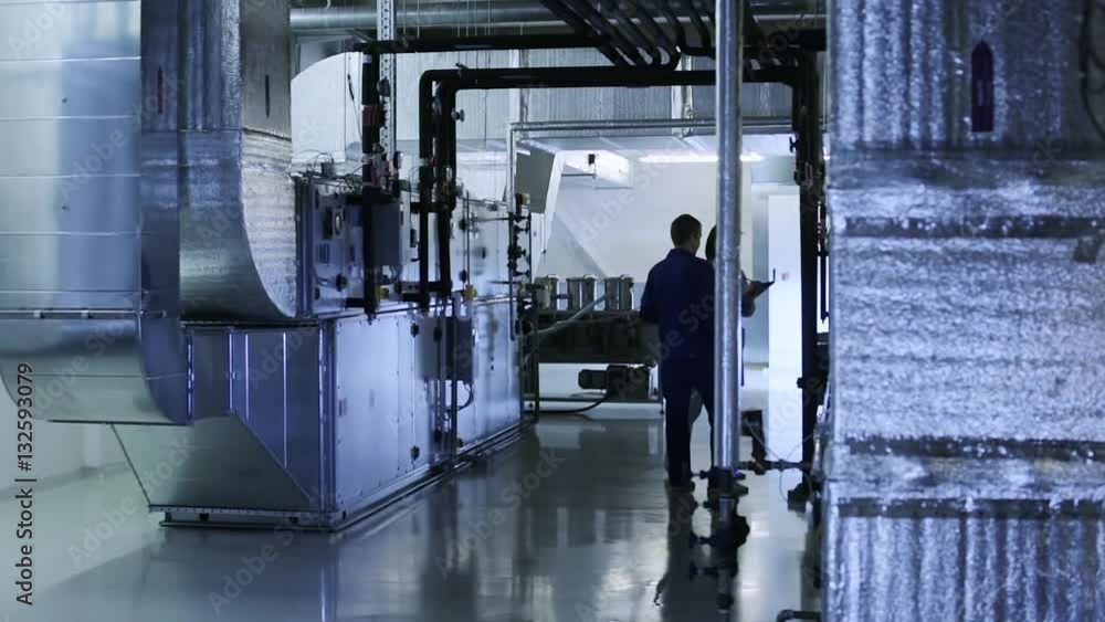 People checks industrial air ducts of a ventilation system on clean and light technical floor