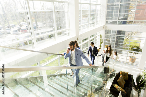 Young man with mobile phone on stairs in modern office