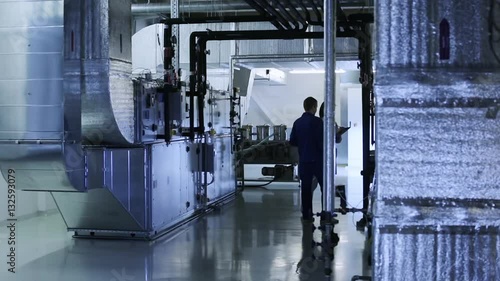 People checks industrial air ducts of a ventilation system on clean and light technical floor