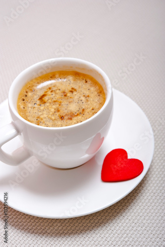a white  cup with espresso and many hearts like a cocept love for coffee
