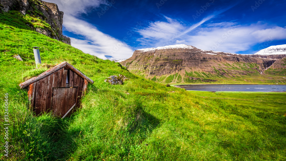 Small mountain hut on grassy hill, Iceland in summer