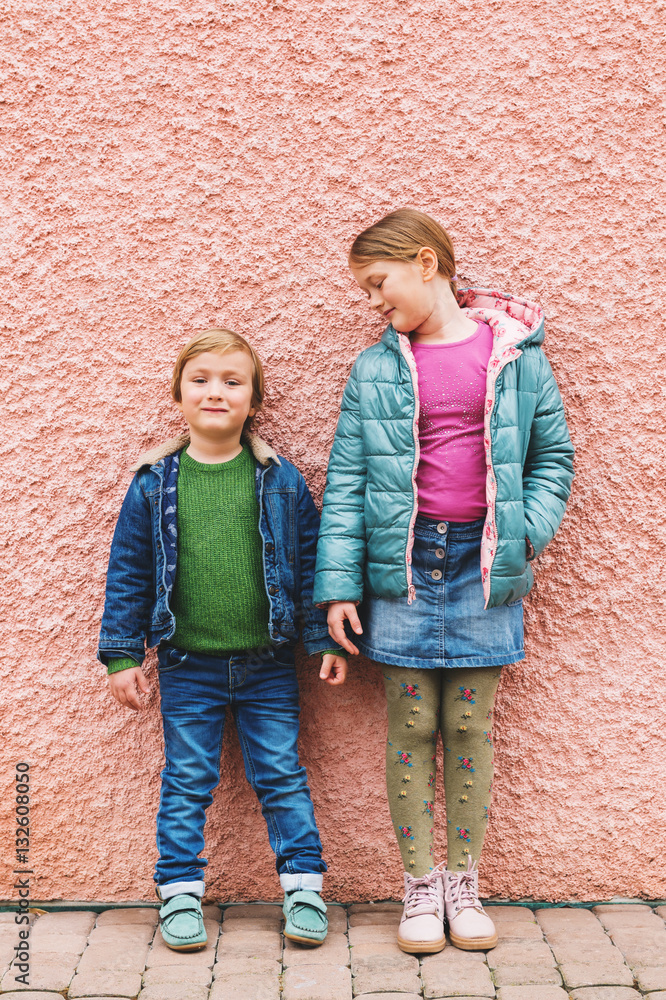 Fashion portrait of adorable kids wearing warm jackets and shoes