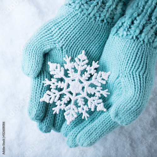 Female hands in light teal knitted mittens with sparkling wonder