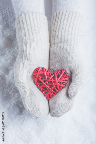 Female hands in white knitted mittens with a entwined vintage ro