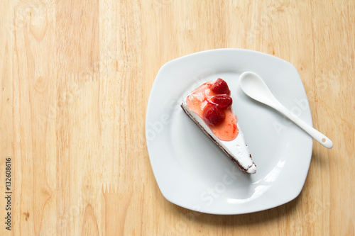 Strawberry cake with white plate on wooden background