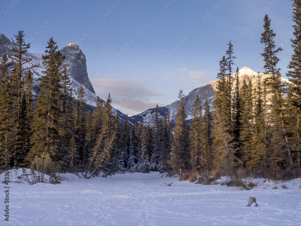 Sunrise view of mountains from a frozen Policemen's Creek along the Bow River outside Canmore, Alberta in winter.