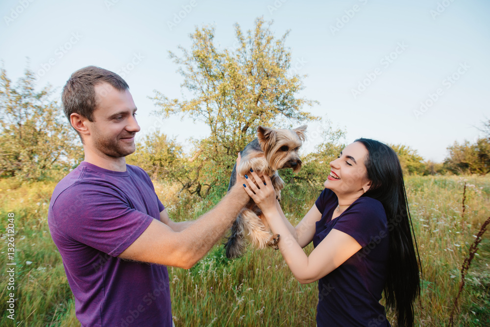 Obraz premium Young happy couple on nature,the boy gives girl a dog - yorkshire terrier as gift ,love,lifestyle,relationship,valentine
