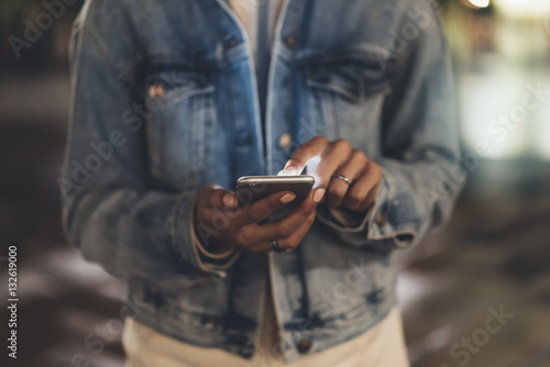 Girl pointing finger on screen smartphone on background illumination bokeh light in night atmospheric city  hipster using hands and texting mobile phone  mockup glitter street  content lifestyle