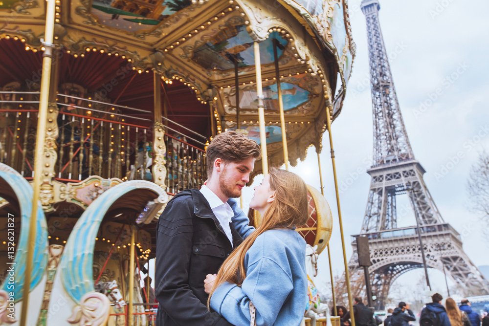 happy couple in Paris, romantic kiss near carousel and Eiffel tower