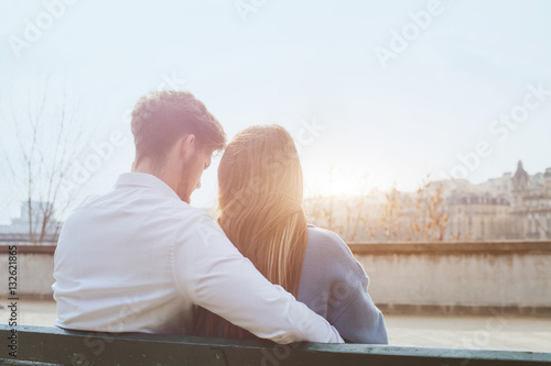 dating or first love, young couple sitting together on the bench, view from the back photo