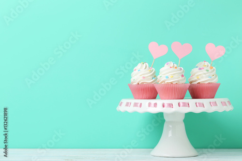 Tasty cupcakes on cake stand on green background