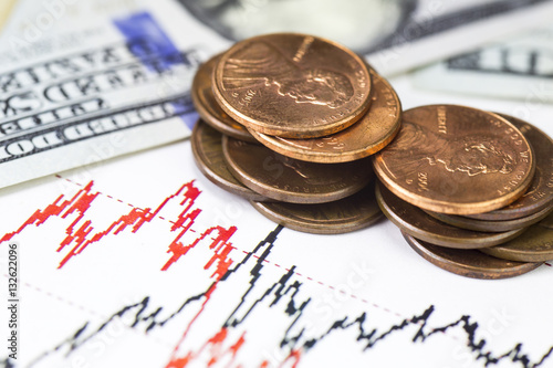 Heap of us cents coins with Lincoln portrait and hundred us dollar bills on Stock market Charts, Us currency, Macro image. Part of Dollar bill with blue ribbon. Red and black lines on the chart.