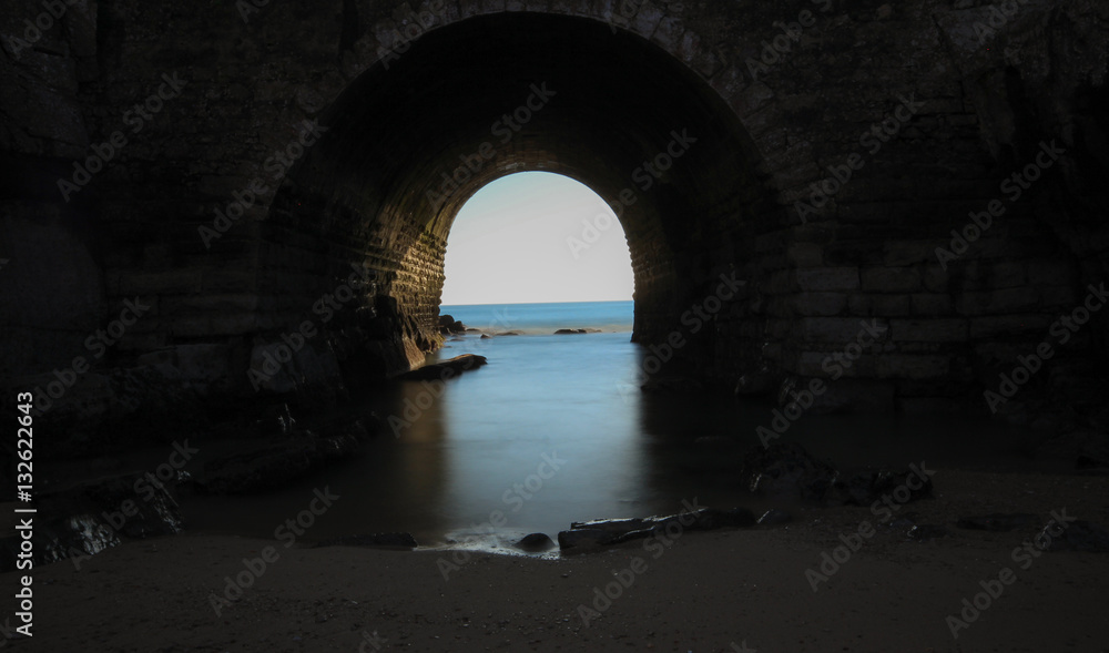 Big stone wall with a tunnel to the sea