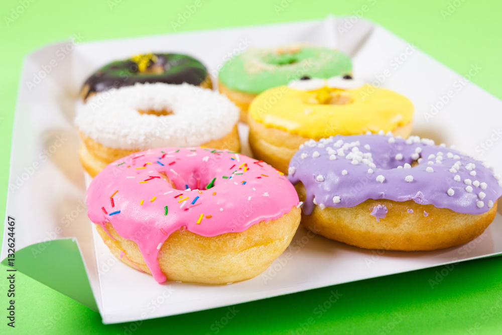 Strawberry, chocklate and other donuts in paper box on blue background Strawberry, chocklate and other donuts in paper box on blue background