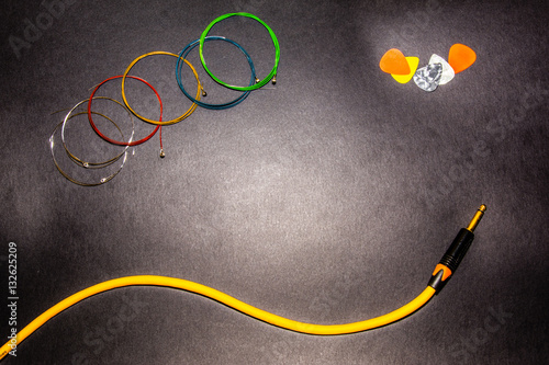 multicolor guitar strings, picks jack cable on grey background