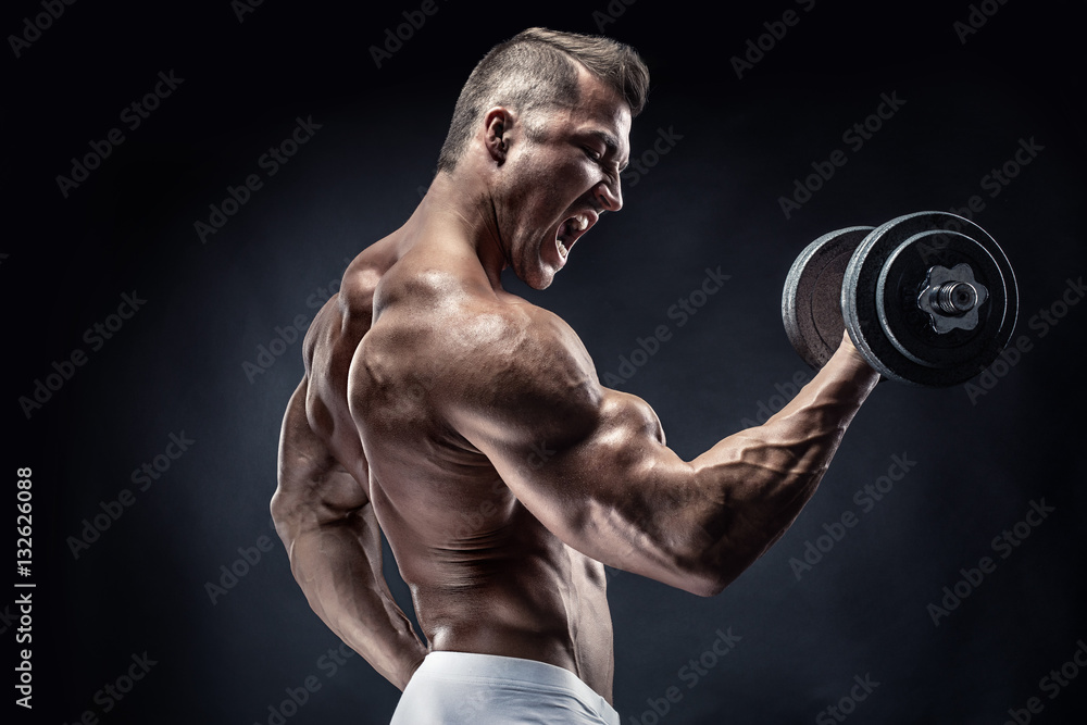 Muscular bodybuilder guy doing exercises with dumbbell