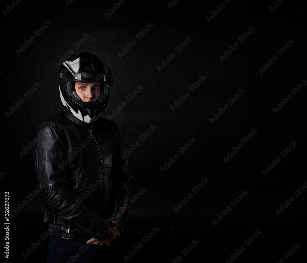 Man moto rider portrait on black background. Sport and extreme boy in motocycle equipment and helmet. Copy space for advertising text or biker goods.