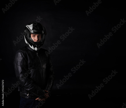 Man moto rider portrait on black background. Sport and extreme boy in motocycle equipment and helmet. Copy space for advertising text or biker goods.