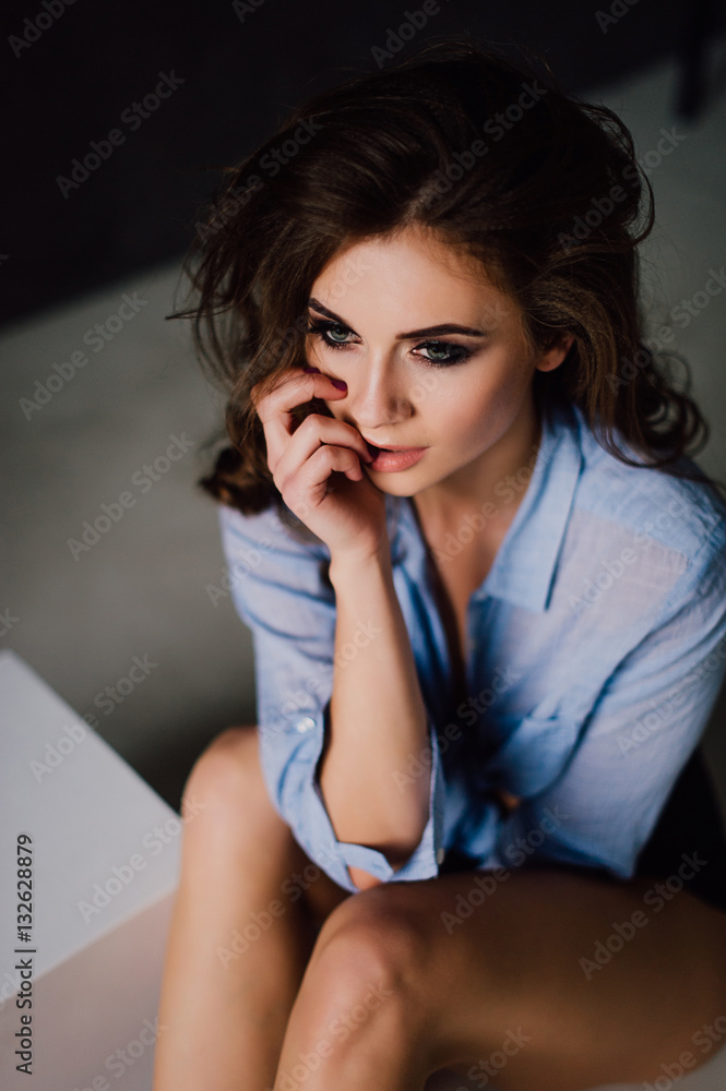 Portrait of sexy young positive woman posing in studio at natural light, wearing blue shirt, has good and healthy fit. Studio retouched shot. Portrait of sexy young positive woman posing in studio at natural light, wearing blue shirt, has good and healthy fit. Studio retouched shot.
