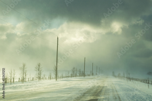 Obraz na plátně Road in winter with ground drifting during a snow squall