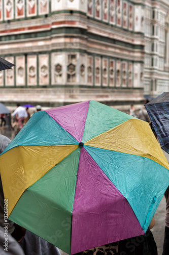 Fototapeta Naklejka Na Ścianę i Meble -  Tourists shelter beneath colorful umbrellas